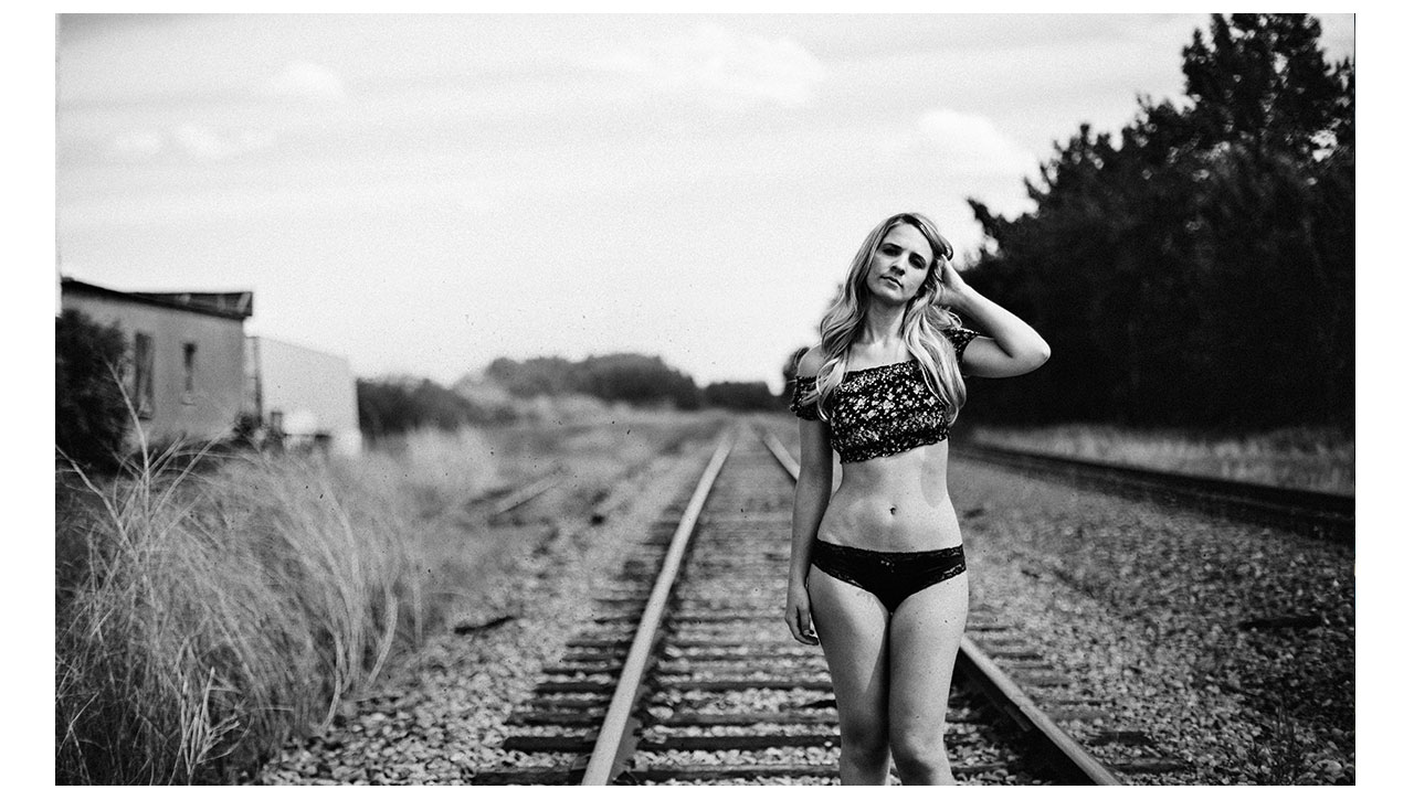 Girl in lingerie walking on train track