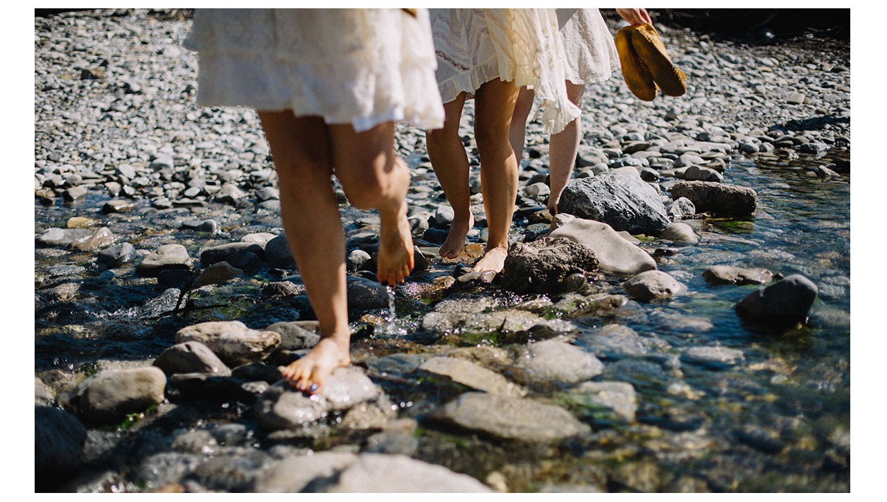 bridesmaids walking through river without shoes